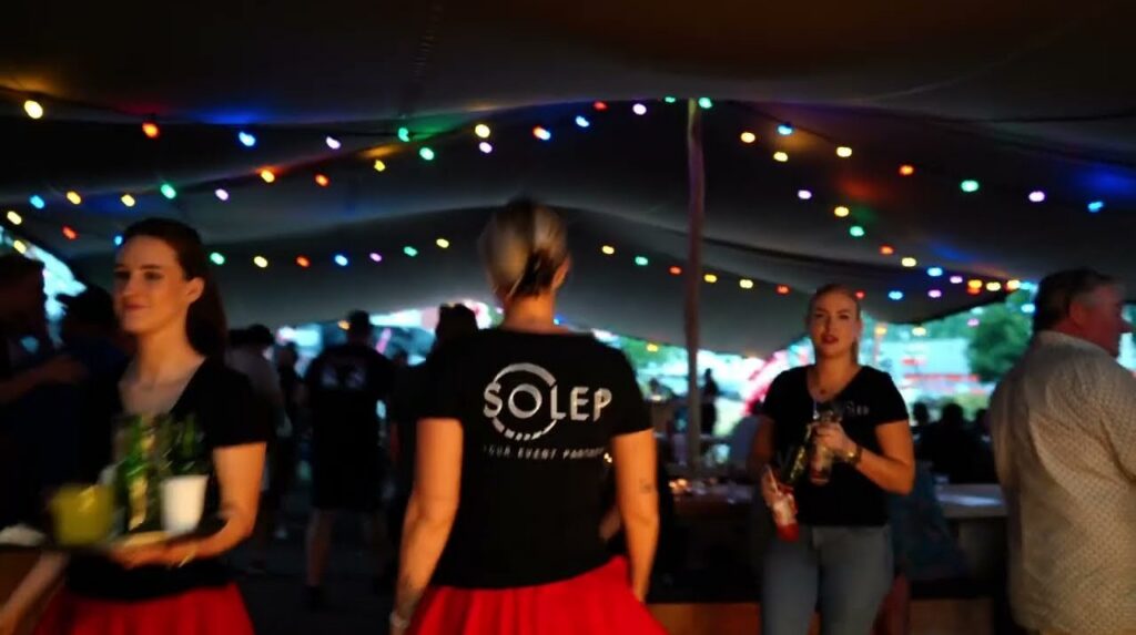 Gasten in een tent met lichtslingers tijdens de zomer-BBQ