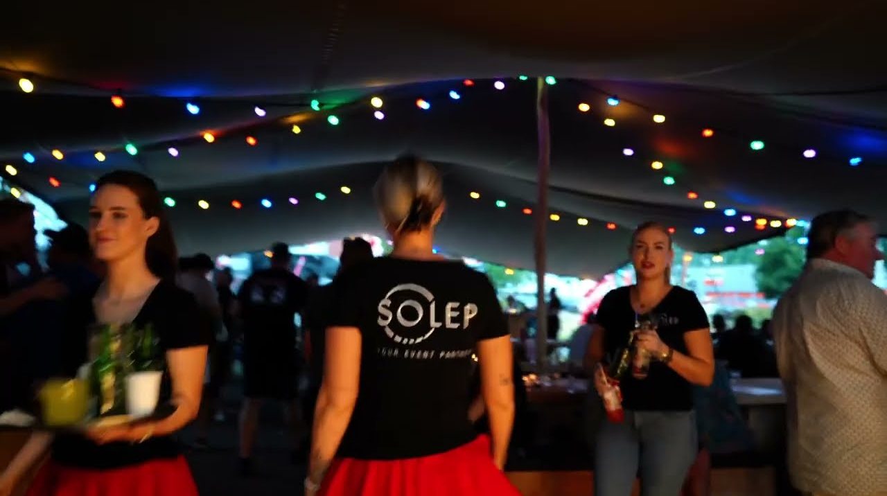 Gasten in een tent met lichtslingers tijdens de zomer-BBQ